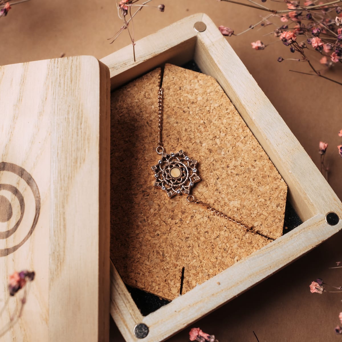 "Aphonia Bracelet", an elegant bracelet with olive and rose gold design, showcased in a rustic wooden box setting.