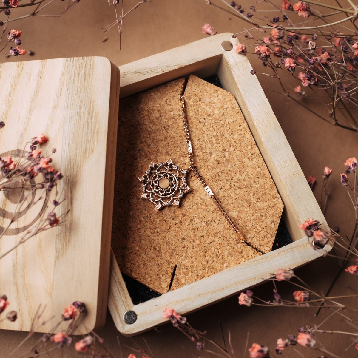 "Aphonia Necklace" necklace featuring an intricate rose gold design with olive accents in a rustic wooden box.