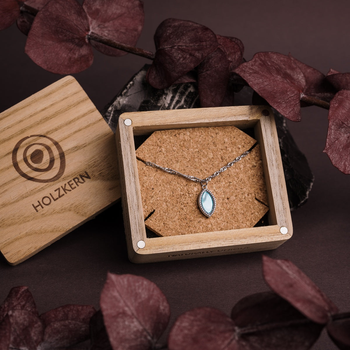 "Visual Necklace", a silver nacre necklace, elegantly presented in a wooden box with a minimalist design.