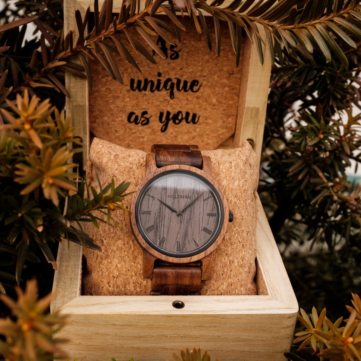 "Spring Evening" watch in Walnut and Leadwood, set in a rustic wooden box surrounded by foliage.