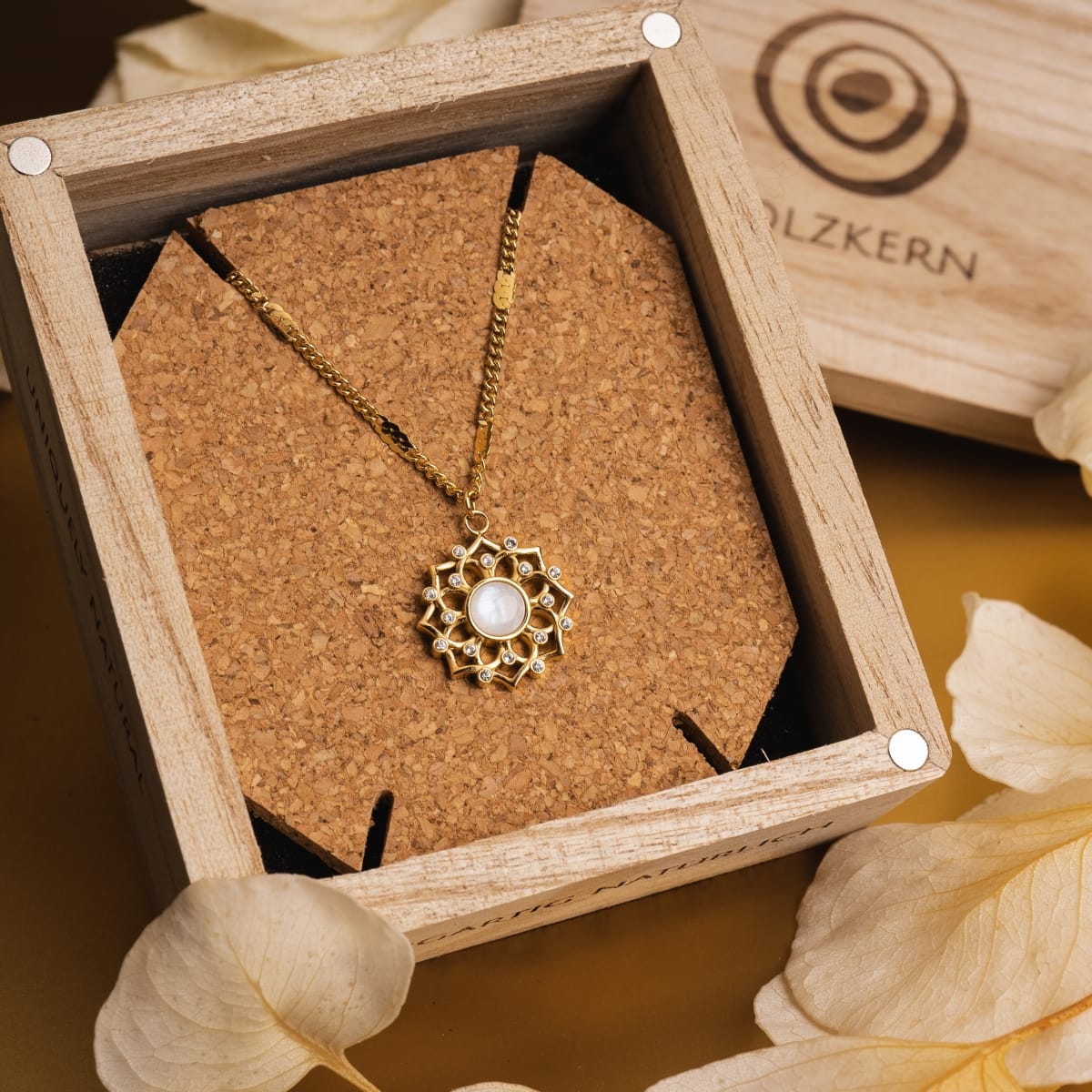 "Composition Gem Necklace", an elegant moonstone and gold necklace with intricate design, displayed in a wooden box.