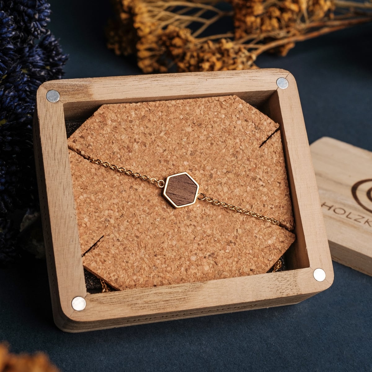 "Facade Bracelet", a stylish walnut and gold bracelet with a hexagonal design, elegantly displayed in a wooden box.