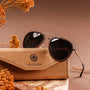 "The Honorable" sunglasses with a stylish leadwood and silver design, presented elegantly on a rustic case.
