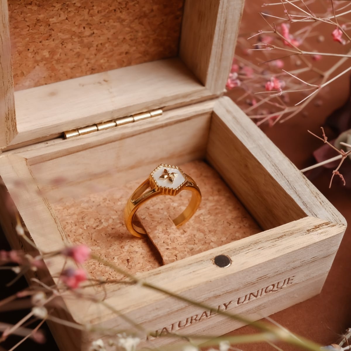 "Spectral Ring" ring with a white nacre and gold design, elegantly displayed in a wooden box.