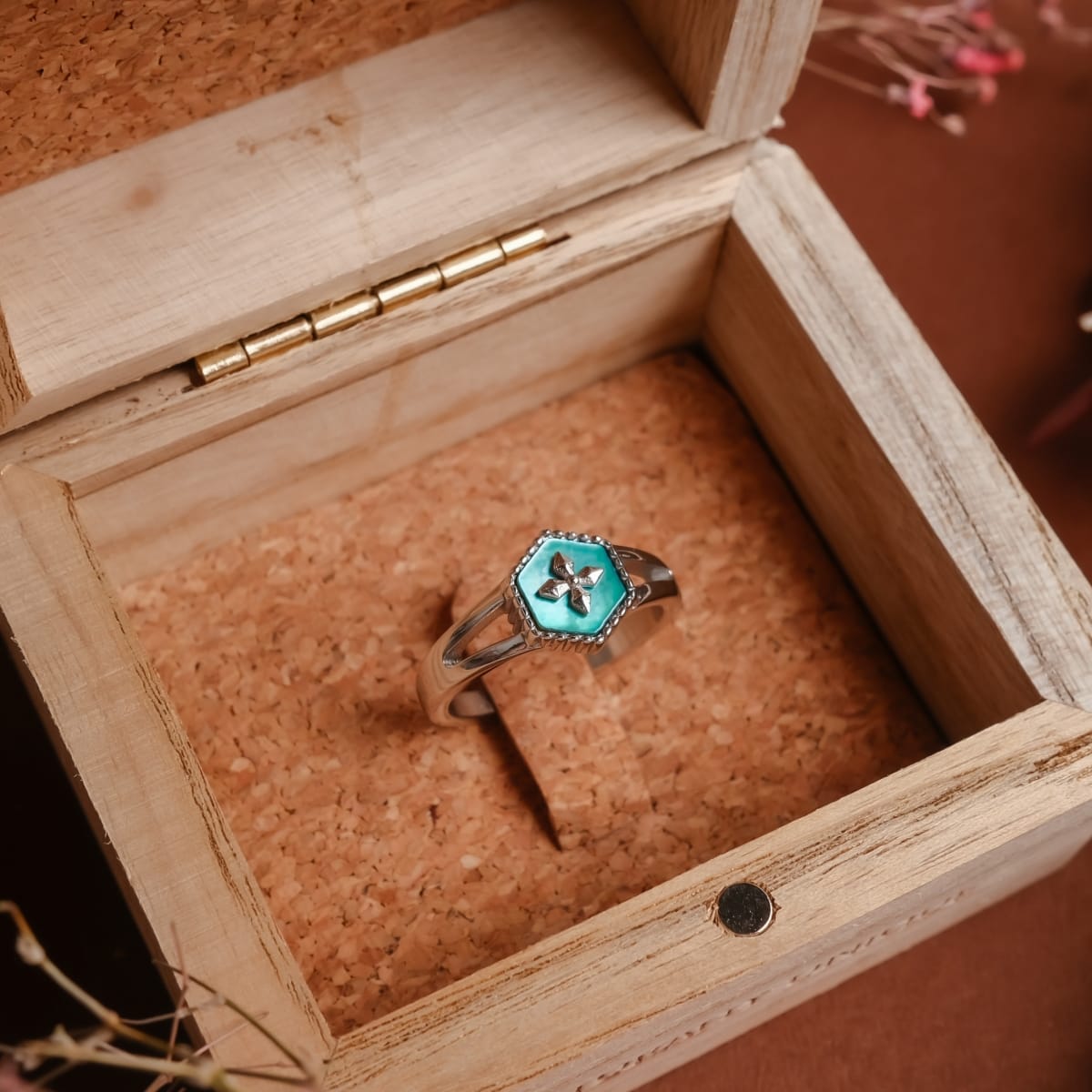 "Spectral Ring", a silver ring featuring a nacre inlay, displayed in a rustic wooden box.