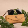 "The Talisman" sunglasses with a walnut and matte gold finish, displayed with a stylish case.
