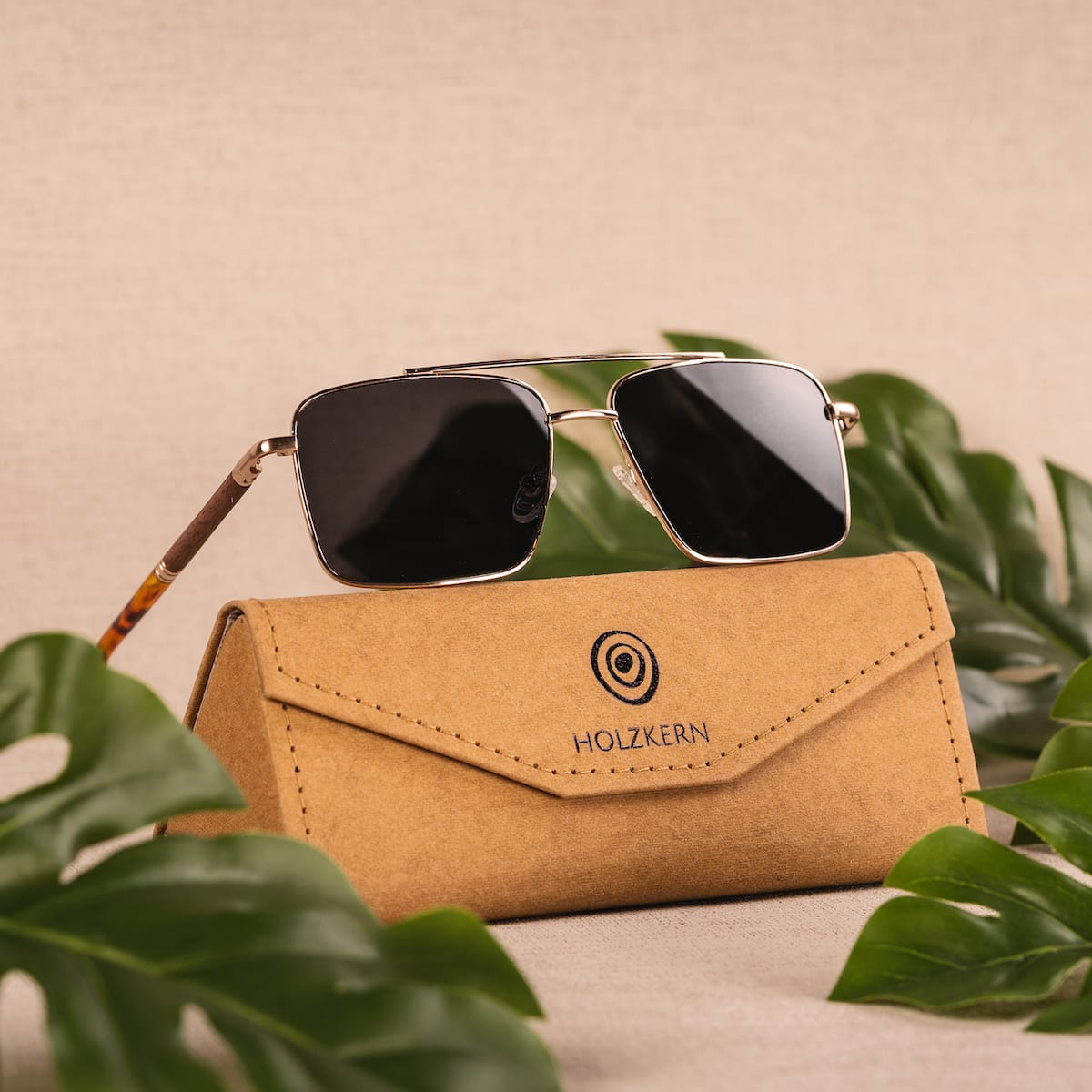 "The Talisman" sunglasses with a walnut and matte gold finish, displayed with a stylish case.