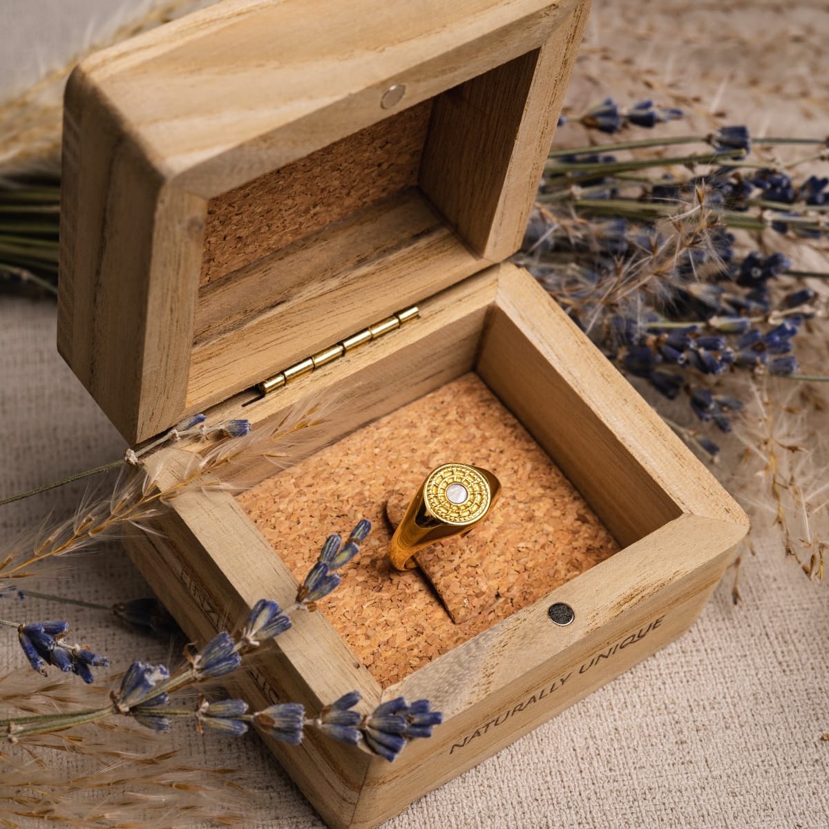 "Pixa Ring" ring featuring a white nacre center set in gold, elegantly presented in a rustic wooden box.