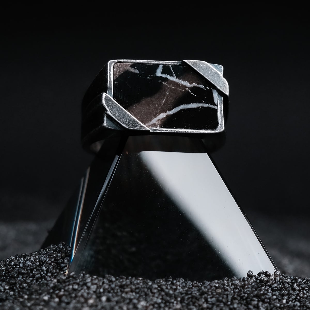 "Binomial Ring" ring featuring a geometric design with marble and antique silver accents, set against a dark background.