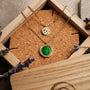 "Zendala Necklace", a stylish necklace with green nacre and gold accents, elegantly displayed in a wooden box.