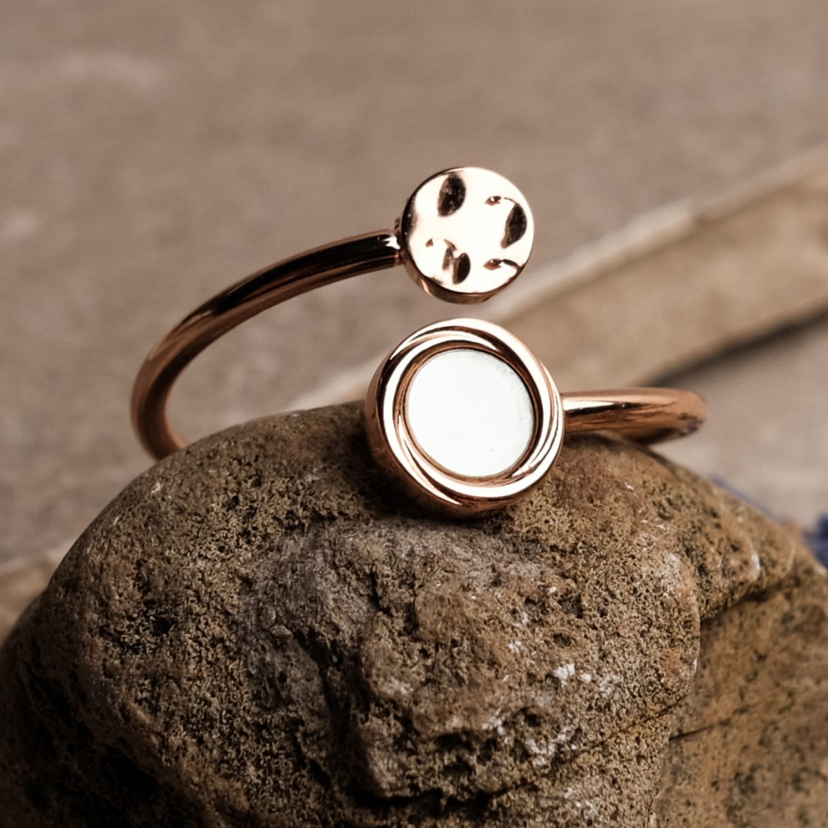"Zendala Ring", an elegant ring featuring nacre and rose gold in a minimalist design, displayed on a stone surface.