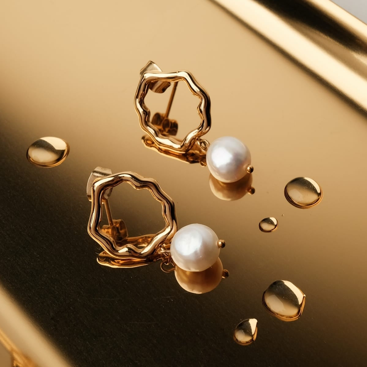 Oceanfoam Earrings feature a pearl and gold design with an ocean-inspired style.