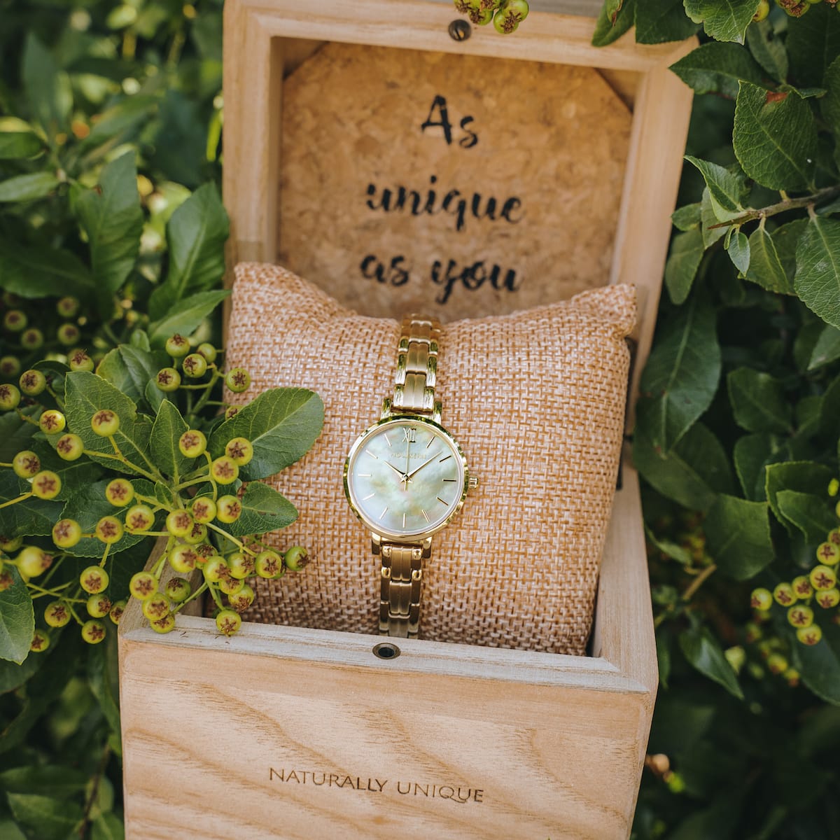 "Themis" watch featuring a nacre dial and gold bracelet, styled elegantly in a natural setting.