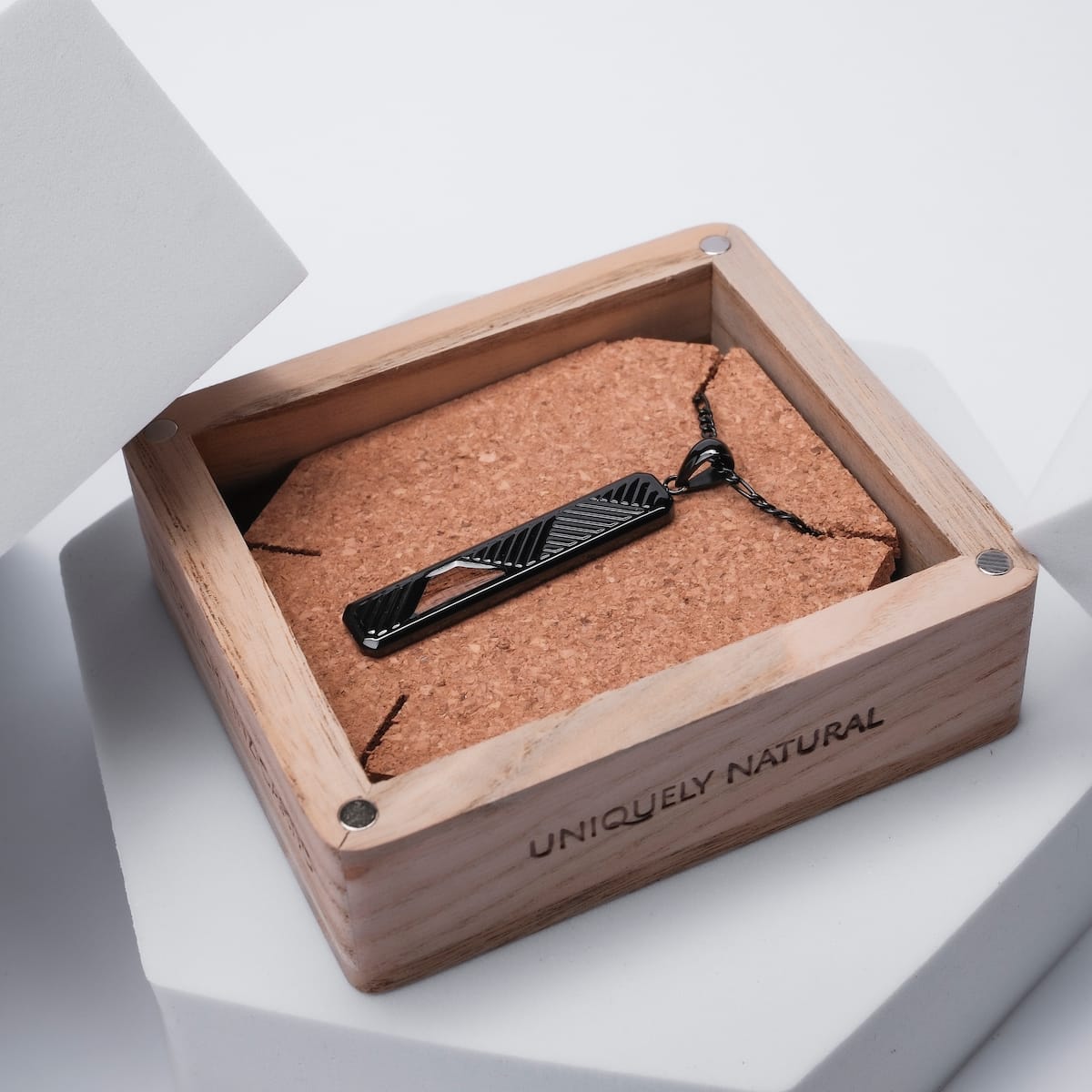 "Derivatives Necklace", a sleek pendant necklace in Zebrawood and black, displayed in a wooden box.