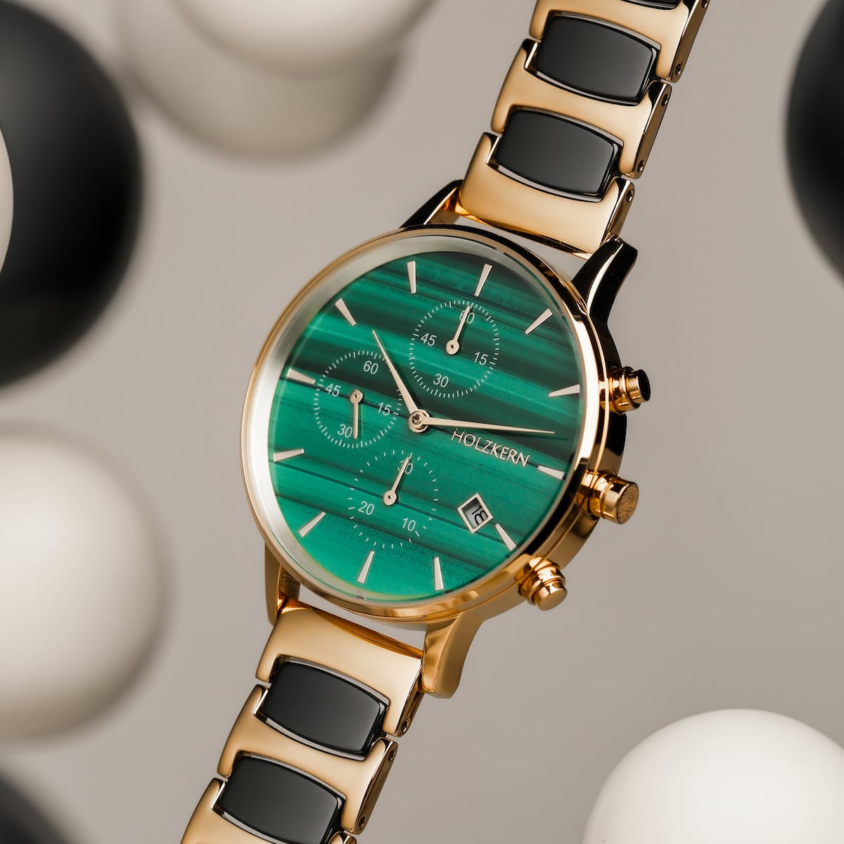 "Jolly" watch with a malachite dial, ceramic and gold accents, showcasing a sleek and elegant design.