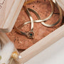"Awakening Necklace" necklace features a sleek marble and gold design, displayed elegantly in a wooden box.