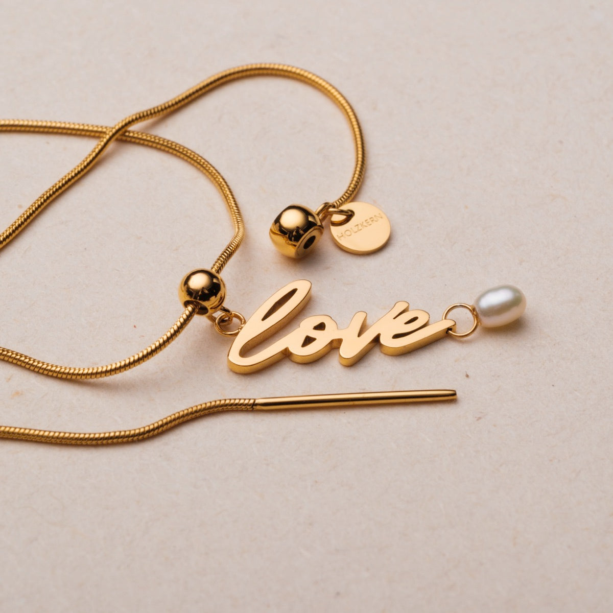 "Love-Charm" necklace featuring elegant gold finish and pearl accent in a stylish design.