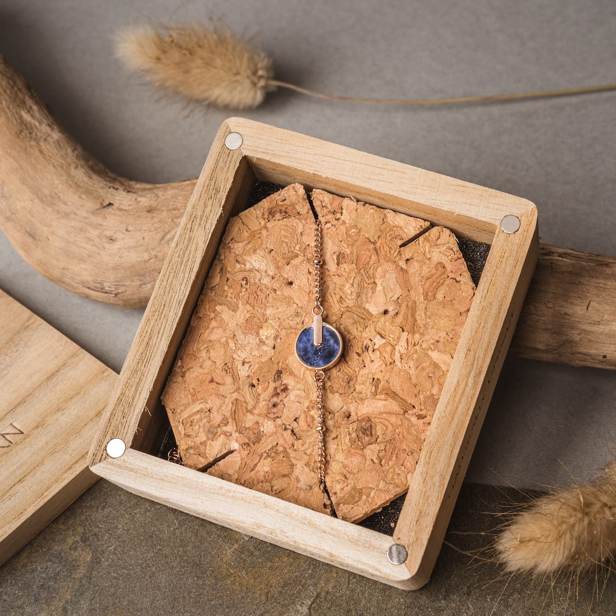 "Opacity Bracelet" bracelet, featuring a blue marble design with rose gold accents, elegantly displayed in a rustic wooden box.