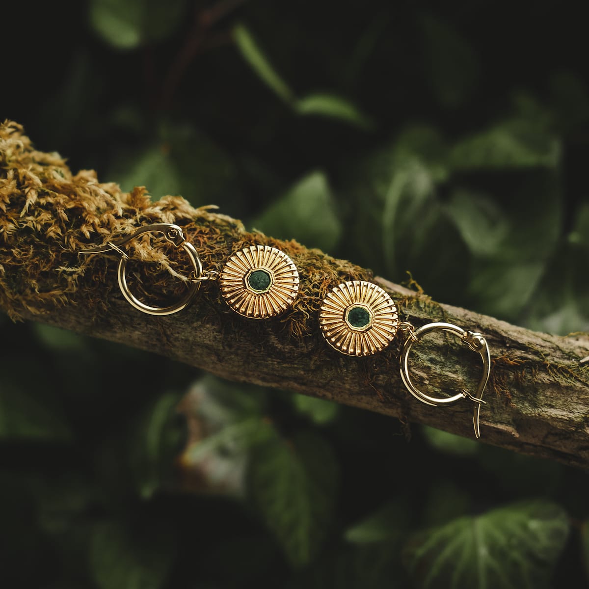 Stencil earrings: Elegant earrings with a marble and gold design, resting on a natural branch background.