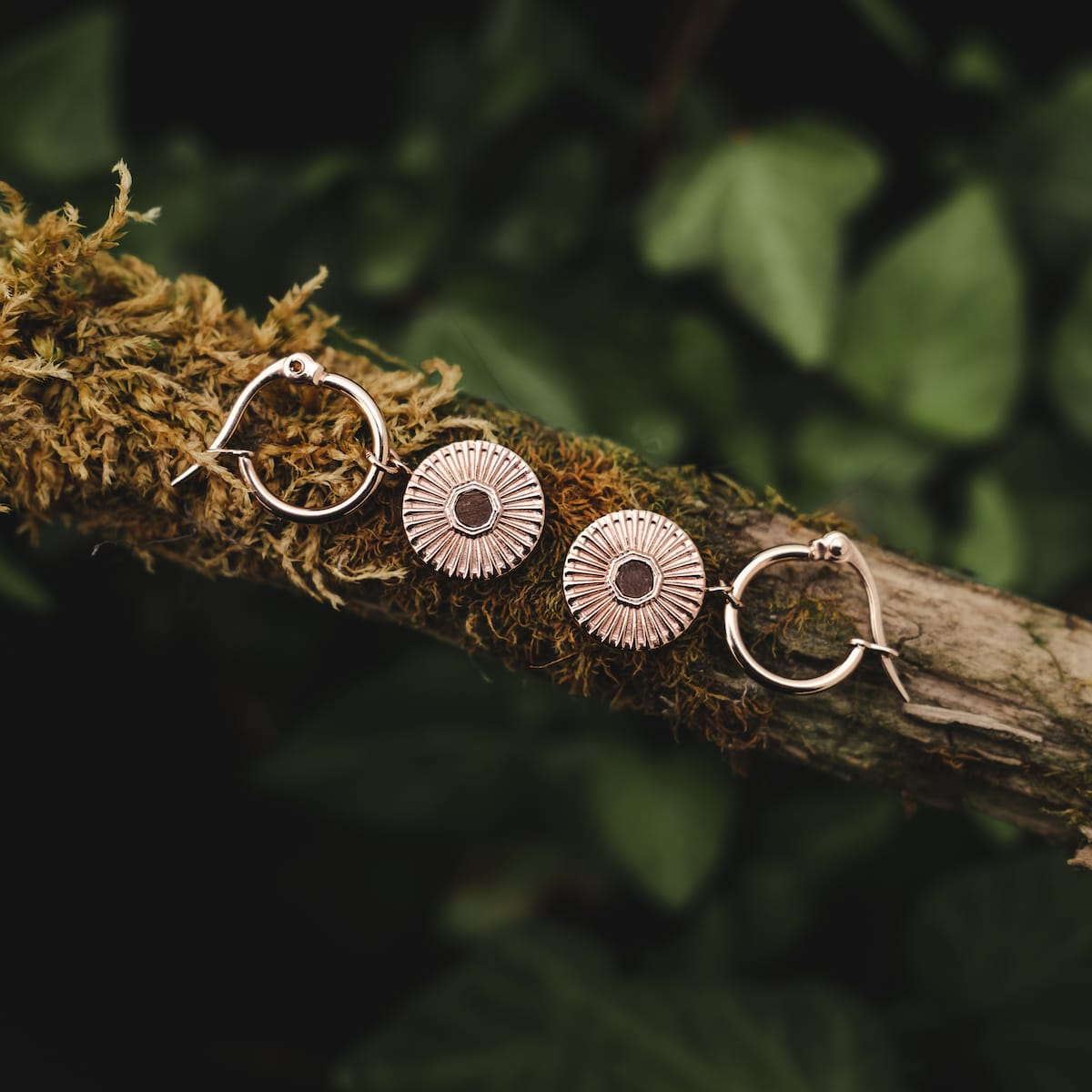 Stencil earrings: Stylish earrings combining walnut detail with rose gold accents on a natural backdrop.