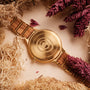 "Capri" watch, featuring a natural wood and gold style, elegantly surrounded by dried botanicals.
