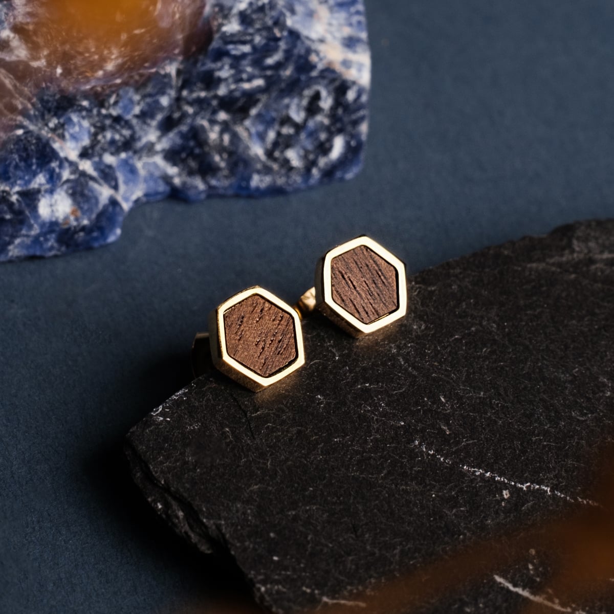 "Facade Earrings" earrings featuring a hexagonal walnut center set in gold, showcasing a modern and elegant style.