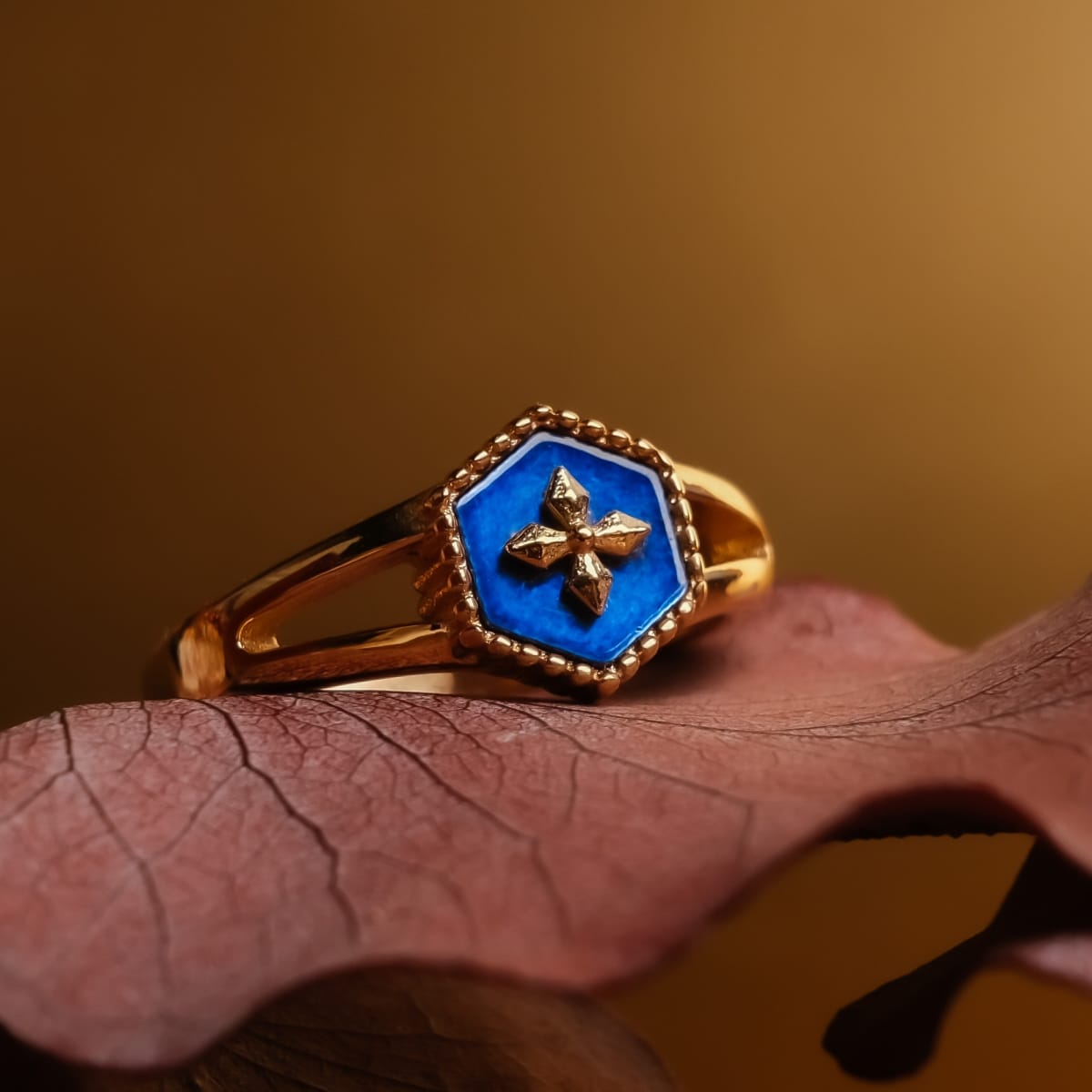 "Spectral Ring" ring featuring a blue nacre and gold design resting elegantly on a leaf backdrop.