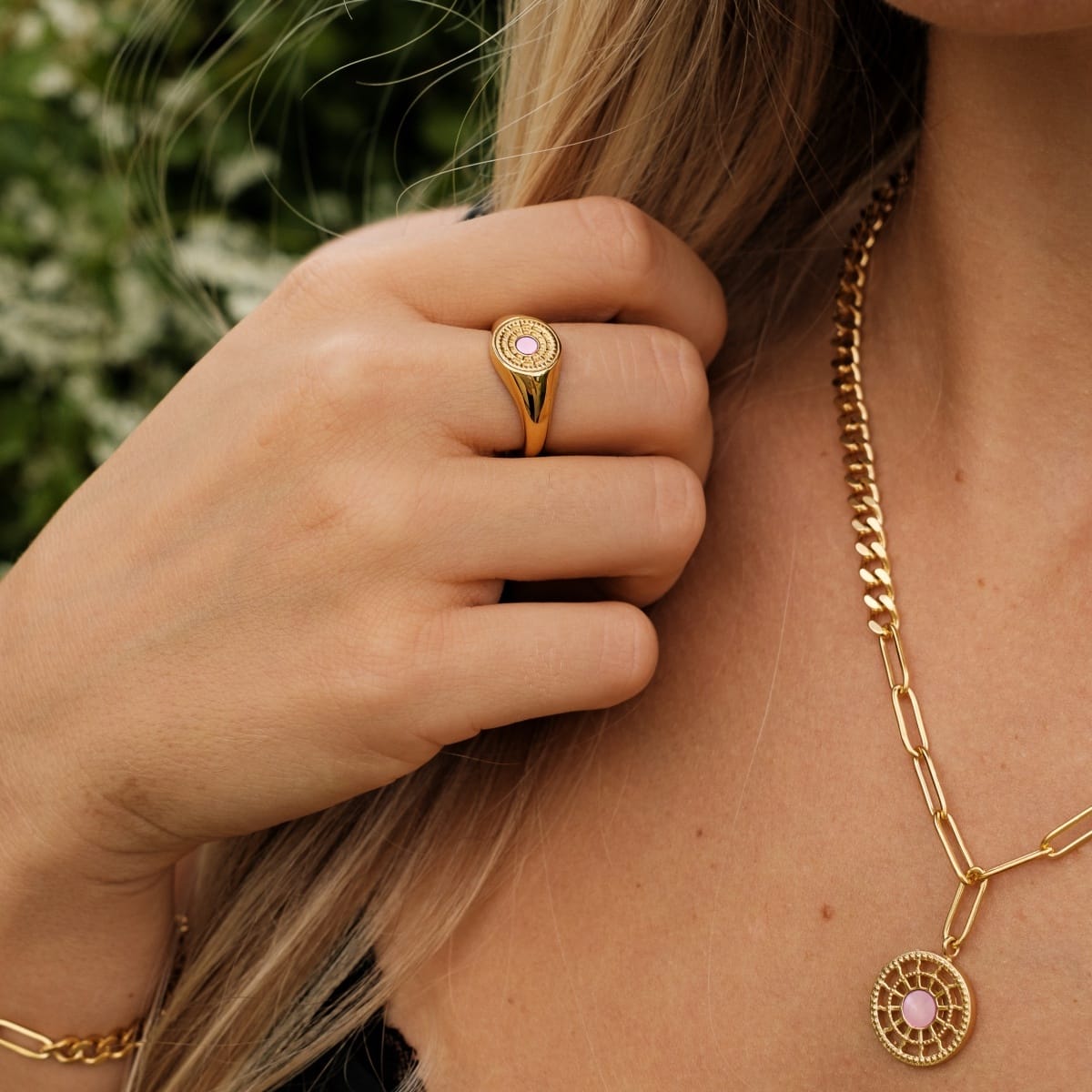 "Pixa Ring", a stylish ring with pink nacre and gold details, worn elegantly on a hand.