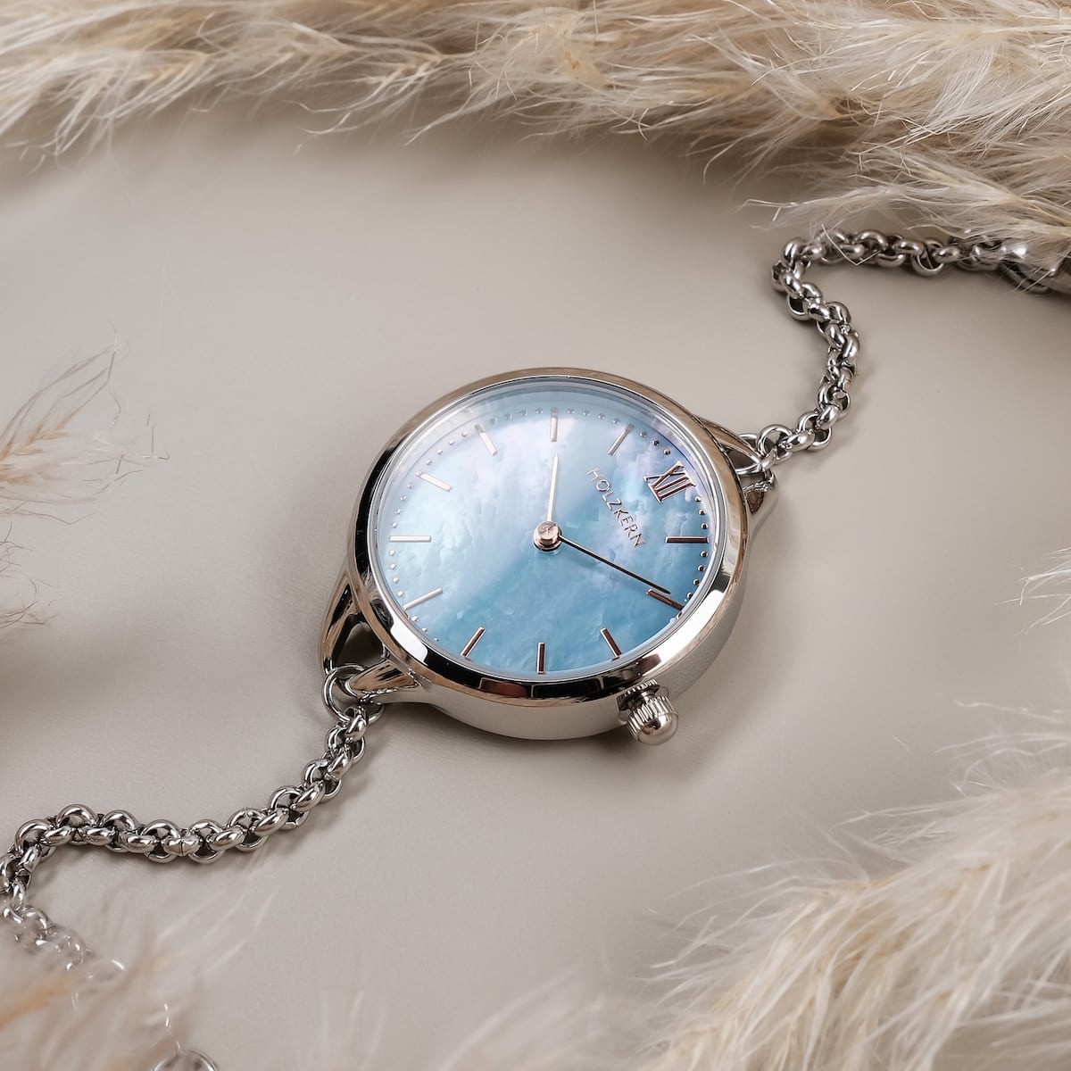"Brighter", a stylish wristwatch with a nacre dial and silver accents, elegantly presented with a chain bracelet.