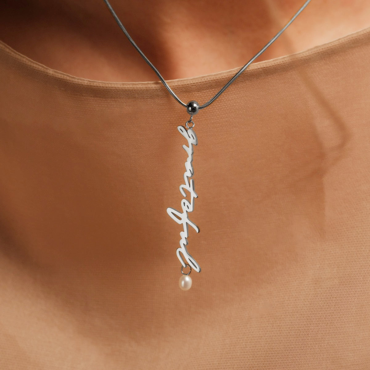 "Grateful-Charm", elegant necklace with a silver charm and pearl accent, showcasing a sleek, minimalist design.