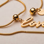 "Love-Charm" bracelet: elegant gold script with delicate pearl accents.