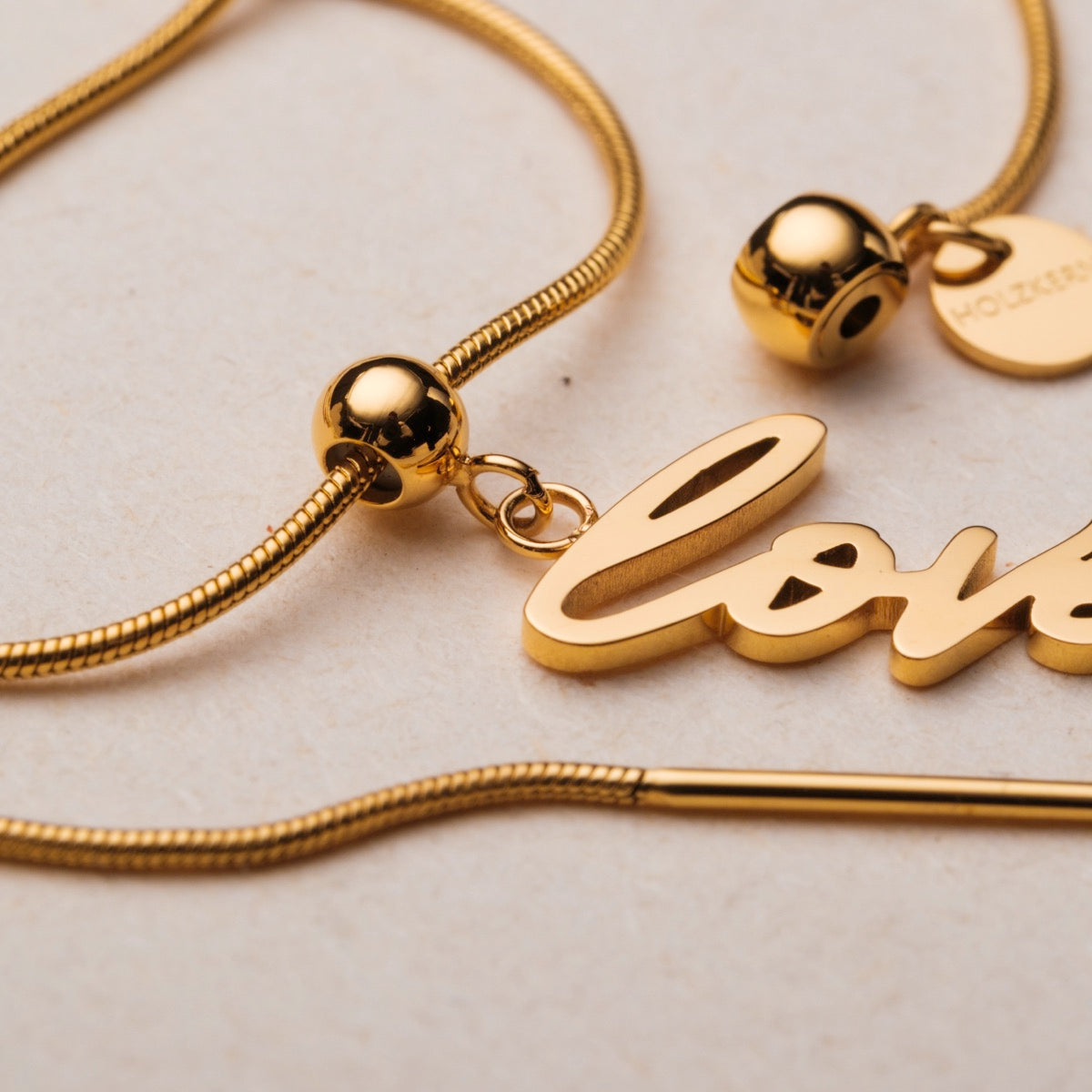 "Love-Charm" bracelet: elegant gold script with delicate pearl accents.