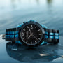 "Glaciersurge" watch features a sleek design with shiny Hawk's eye and Maple detailing, set against a tranquil water background.
