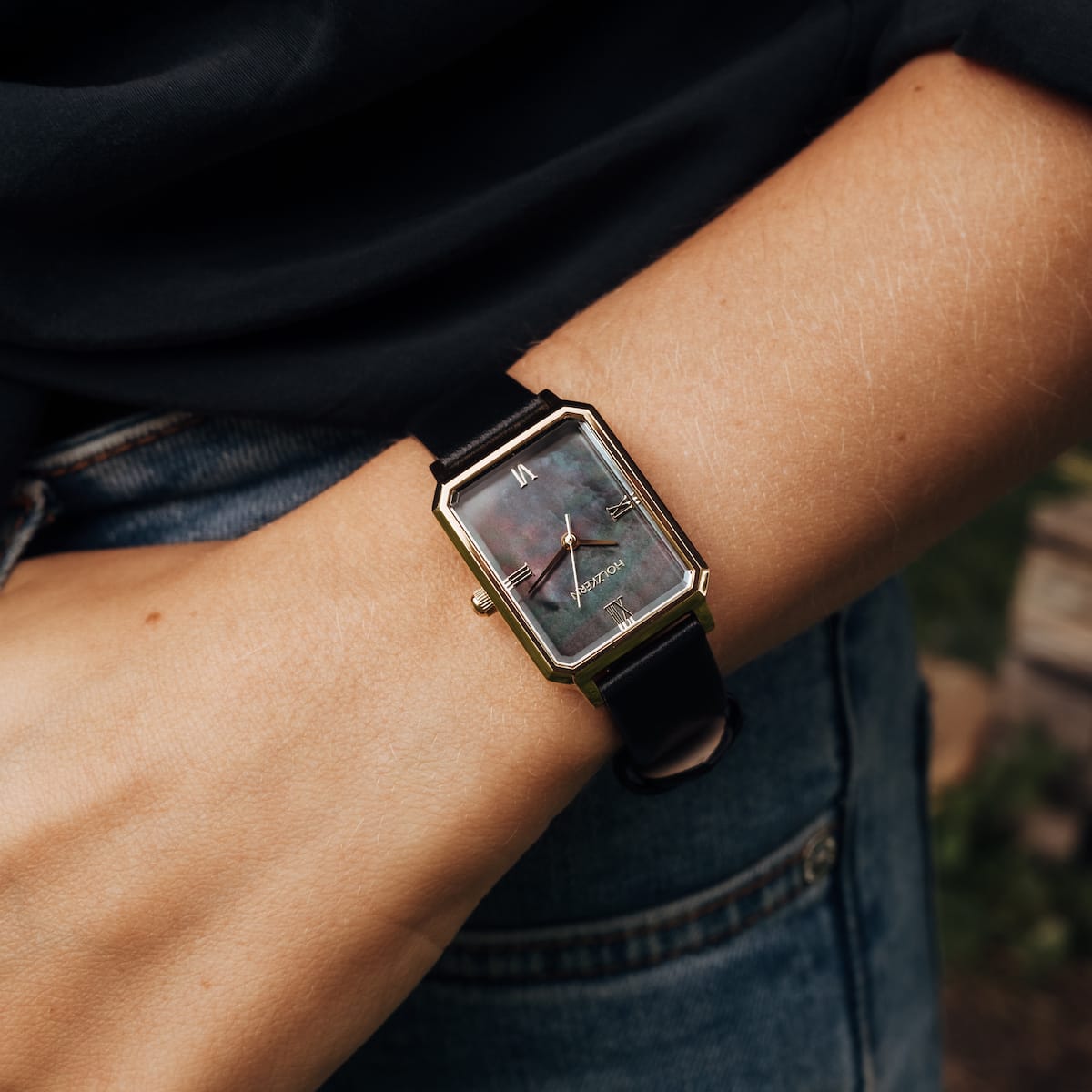 "Auctoritas", a stylish watch in nacre and gold with a sleek rectangular face and black strap.