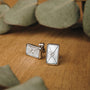 "Aquarell Earrings": Elegant rectangular earrings with white nacre and silver detailing, set on a wooden surface.