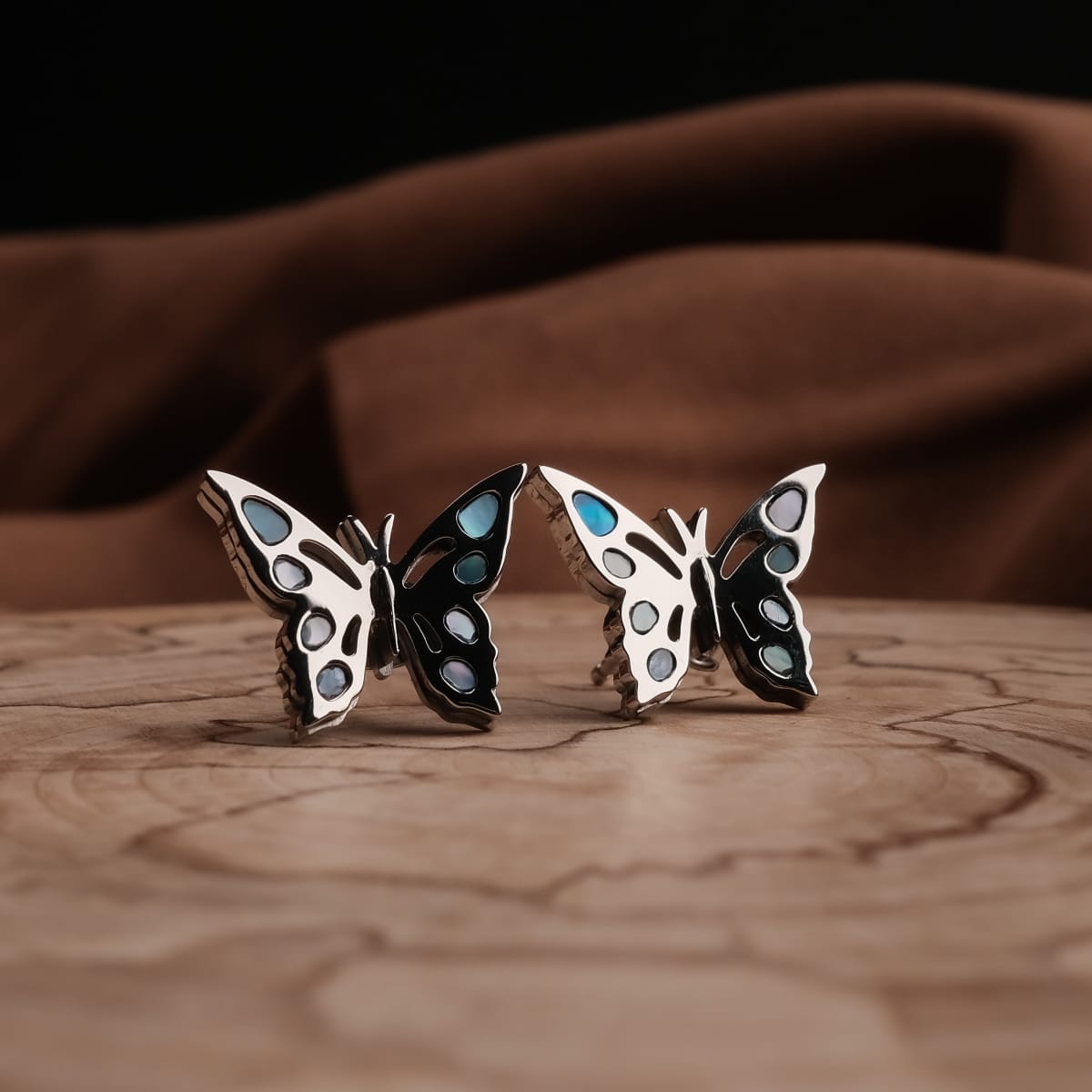 "Fritillary Earrings" butterfly earrings featuring a stylish nacre and silver design on a wooden surface.