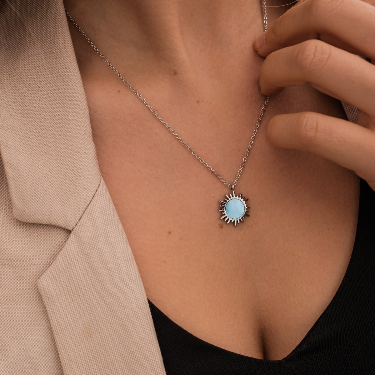 "Shade Necklace" necklace featuring a blue nacre pendant in a sunburst design with a silver chain.