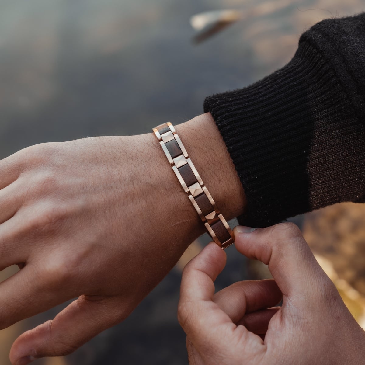 "Rhapsody" bracelet in walnut and rose gold, showcasing a stylish, sophisticated design on a wrist outdoors.