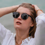 "The Trustworthy" sunglasses with a sleek, modern style featuring dark lenses and an elegant frame design.