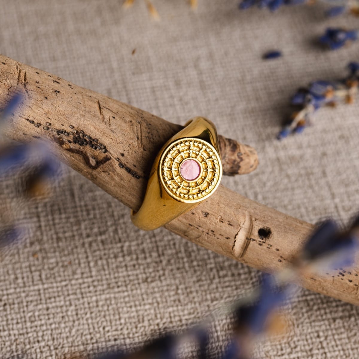 "Pixa Ring" ring with a pink nacre and gold design, set against a natural wood backdrop.