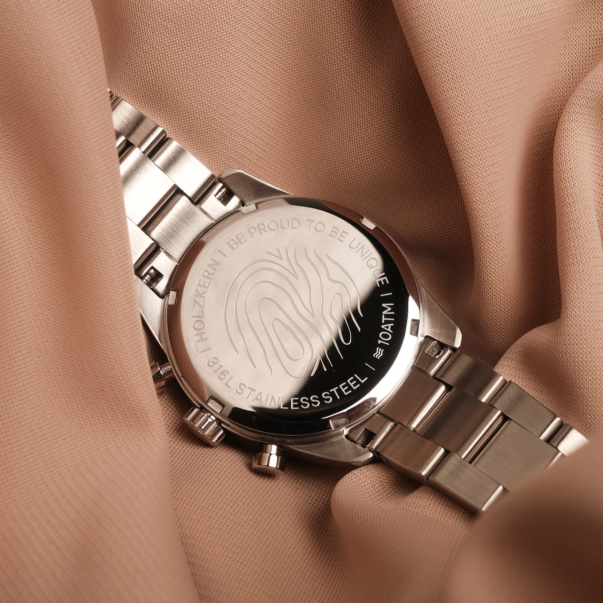 "The Balanced" watch with nacre and silver accents, featuring a sleek and modern design on a stainless steel backdrop.