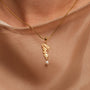 "Love-Charm" necklace, featuring gold lettering and a pearl, designed with an elegant, delicate style.