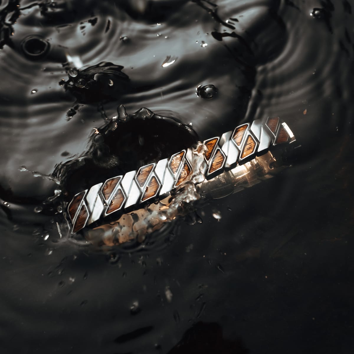 "Baritone" bracelet in Walnut and Silver, featuring a sleek, modern design submerged in water.