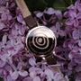 "Shirin" watch featuring walnut and rose gold elements, surrounded by lilac flowers.
