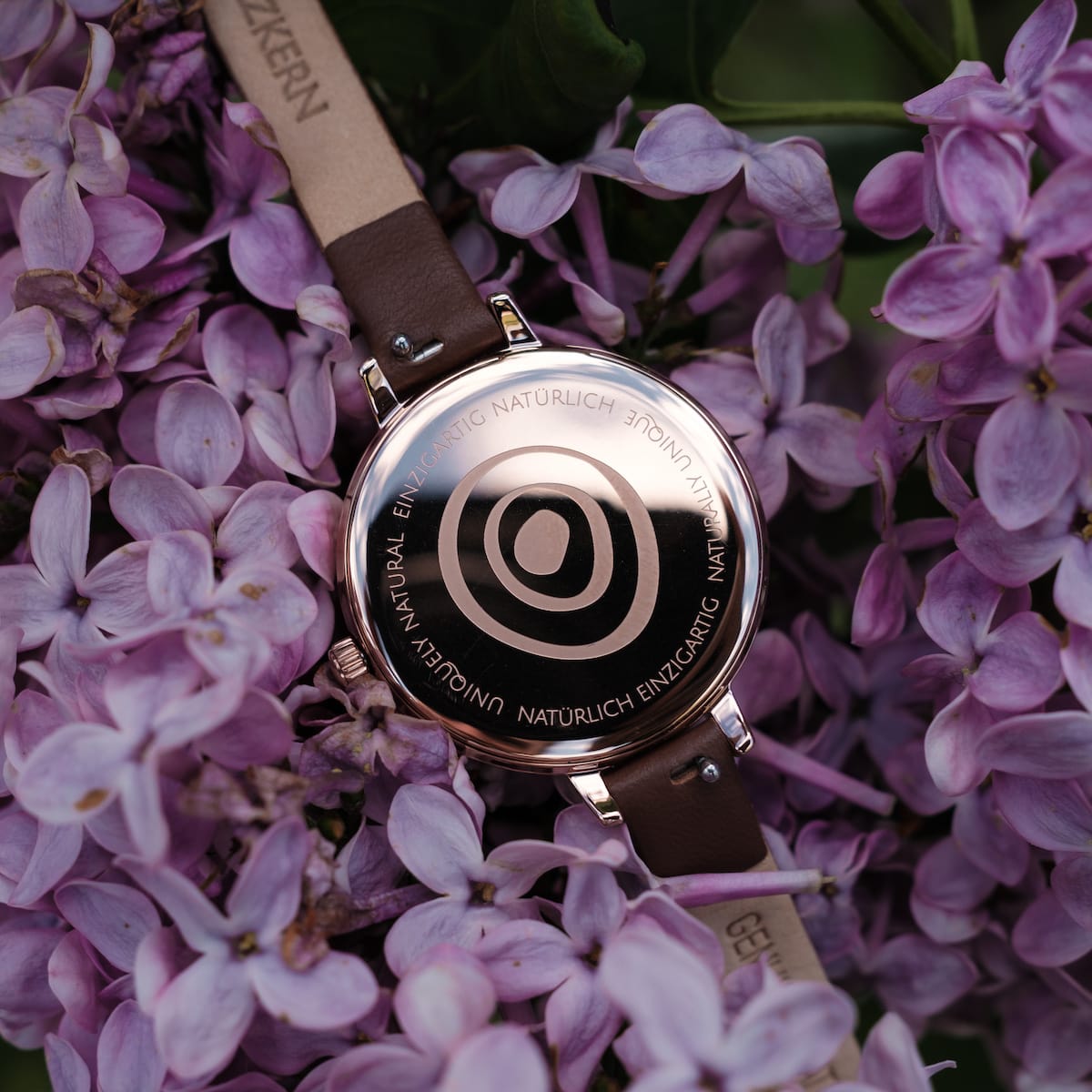 "Shirin" watch featuring walnut and rose gold elements, surrounded by lilac flowers.