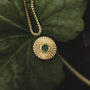 "Stencil Necklace" necklace with a round gold pendant featuring a marble center on a leaf background.