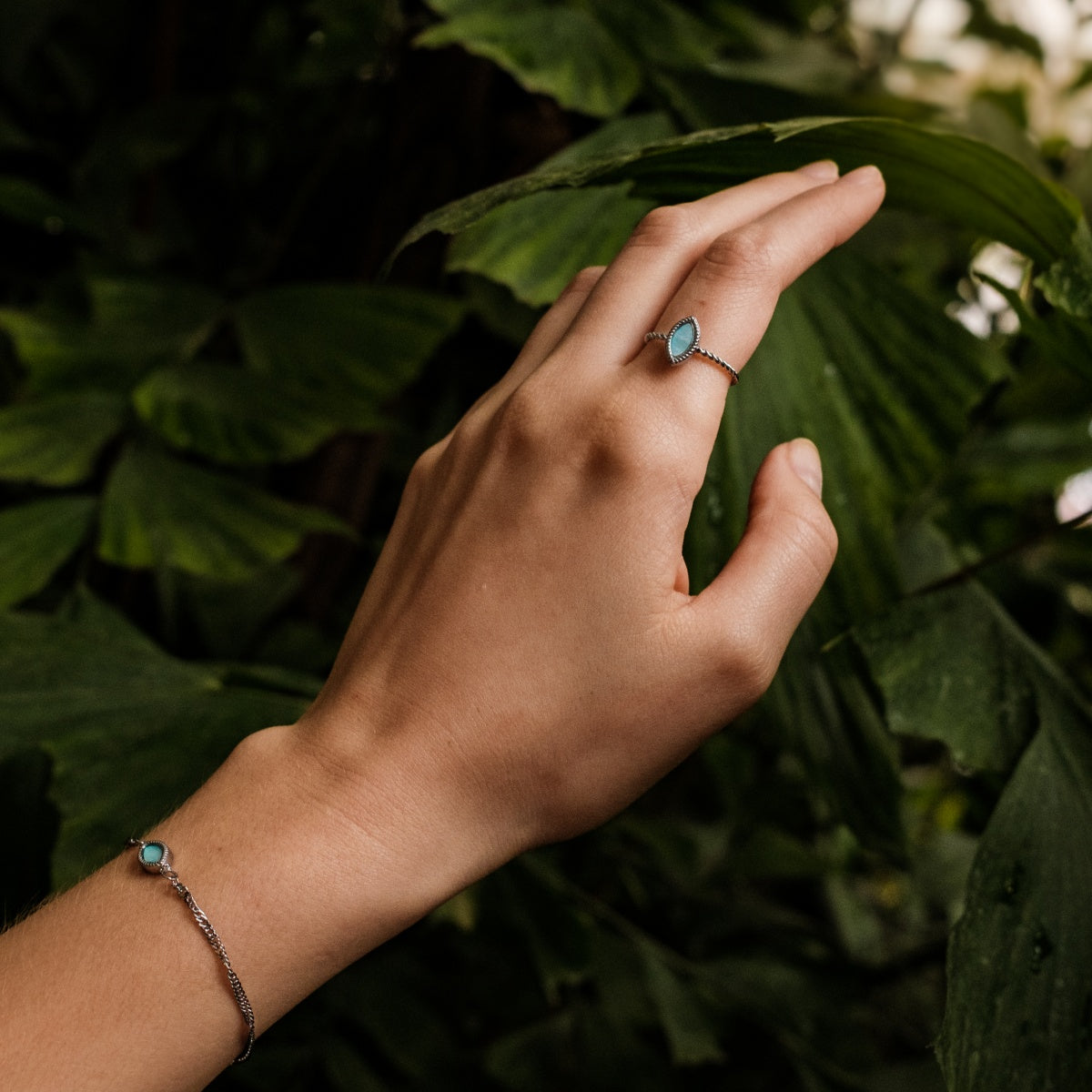 "Visual Ring" ring, featuring nacre and silver, worn against a lush green background for an elegant look.