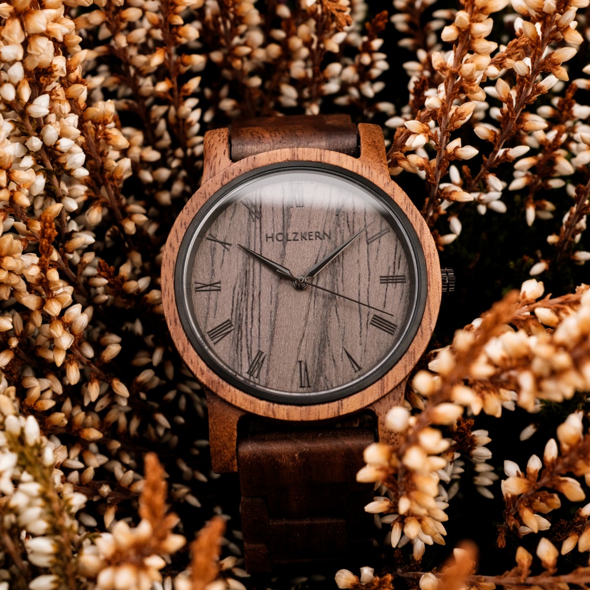 "Spring Evening", a stylish wooden watch, features a natural walnut and leadwood design, set against a backdrop of rustic foliage.