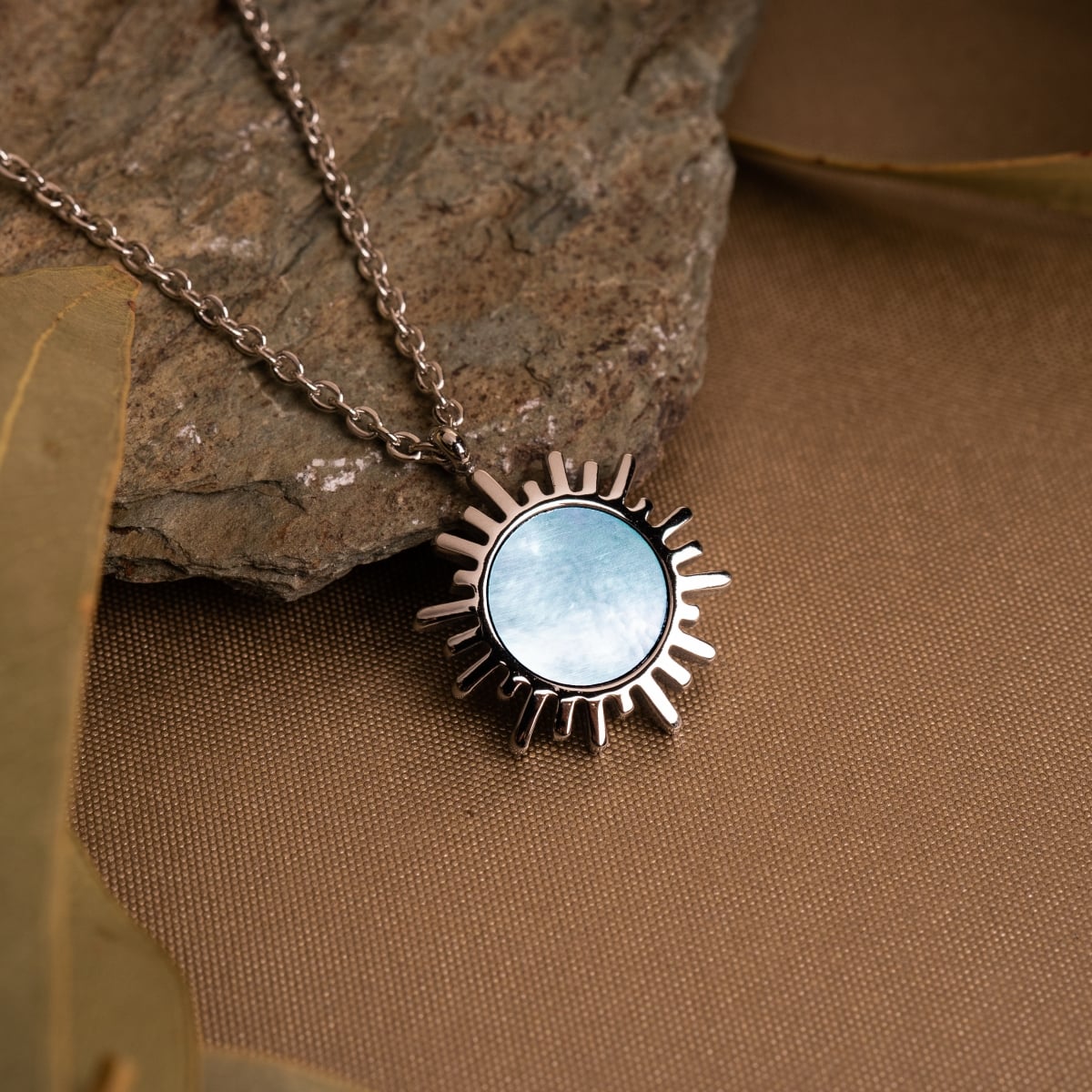 "Shade Necklace" - a sunburst-inspired necklace featuring blue nacre and silver tones.