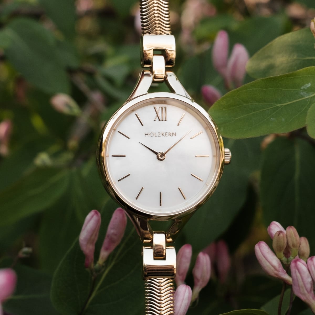 Elegant "Kaliya" watch with a nacre face and gold accents, styled with a floral background.